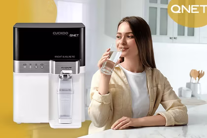 A young lady drinking water from Cuckoo water purifier