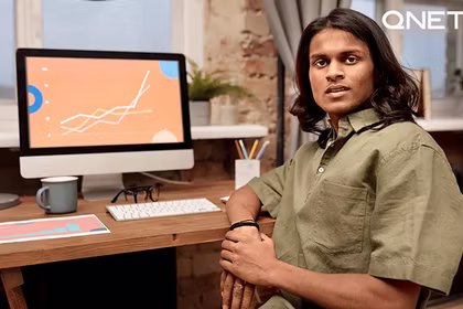 A-man-sitting-in-front-of-his-computer-with-a-sales-graph-going-upwards-on-the-screen