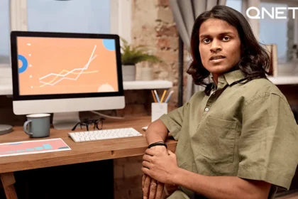 A-man-sitting-in-front-of-his-computer-with-a-sales-graph-going-upwards-on-the-screen