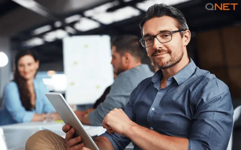 confident young man working with two people behind