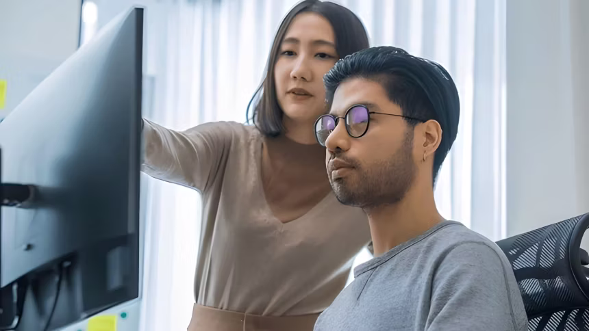 man looking at computer while woman is pointing on screen